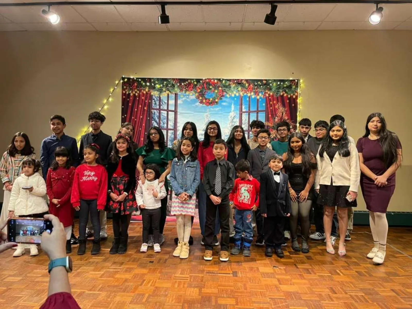Holiday Party group photo with families and the festive backdrop